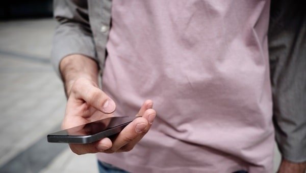 A man holding a cell phone, representing the best nonprofit text platform for communication and outreach.